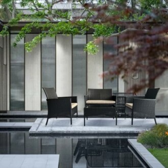 Modern outdoor patio with wicker furniture set on a platform over a reflective pool.