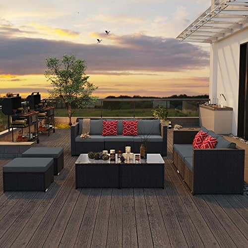 Outdoor patio furniture set with sofas and table on wooden deck at sunset.