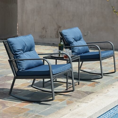 Two blue cushioned patio chairs with a small table by a pool.