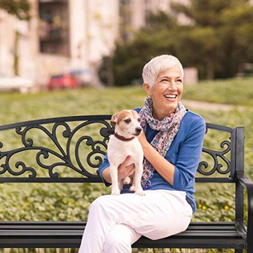 Woman sitting on a decorative bench holding a small dog.